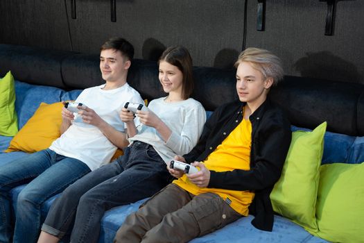 Group of friends of teenagers, boys and girls playing video games on a console in a game club.