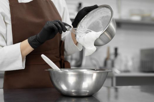 Pastry chef adds whipped cream to a white chocolate mousse.