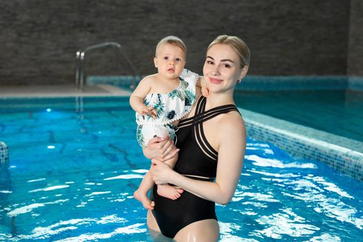 Portrait of a young mother and baby daughter in the pool after a workout.