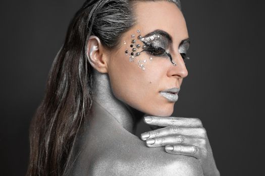 Portrait of a beautiful woman with silver paint on her skin and hair.