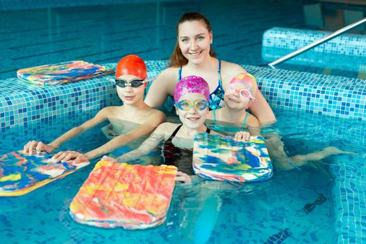 Young girl swimming instructor with children in the pool