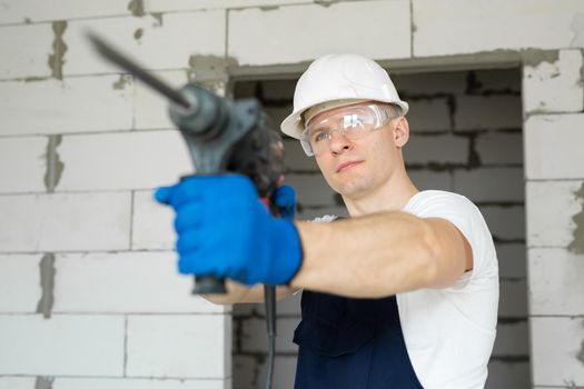 Close-up of a drill in the hands of a professional builder.