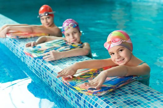 Children in the pool with swimming boards during training.