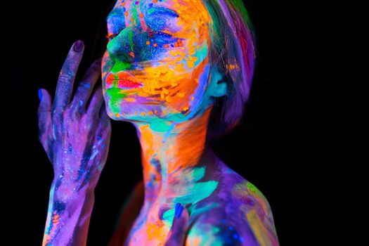 Beautiful young woman in neon light. Portrait of a model with fluorescent makeup posing in UV light with colorful makeup