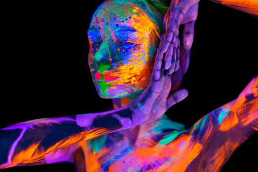 Beautiful young woman in neon light. Portrait of a model with fluorescent makeup posing in UV light with colorful makeup