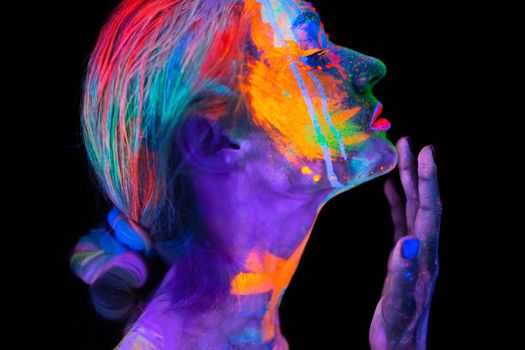 Beautiful young woman in neon light. Portrait of a model with fluorescent makeup posing in UV light with colorful makeup