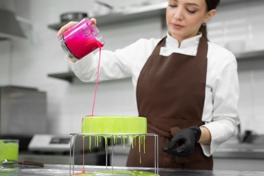 Female pastry chef decorates a mousse cake with a mirror glaze.