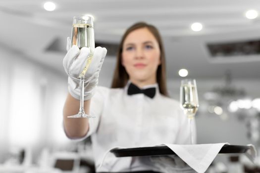 Close-up of a champagne glass in the hands of a waiter sommelier