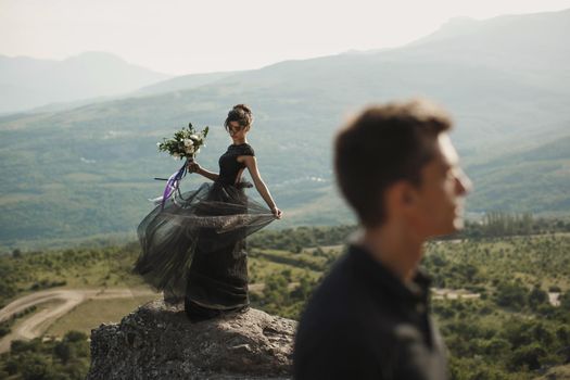 Woman and man in black clothes outdoors. Black wedding dress.