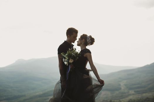 Woman and man in black clothes outdoors. Black wedding dress.