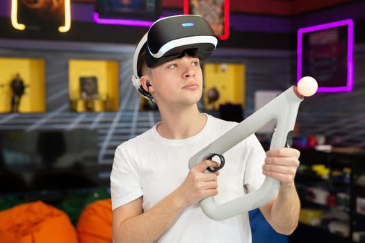 Teen, boy playing on a video game console, emotional gamer shooting a game using a gun controller in a game club. VR