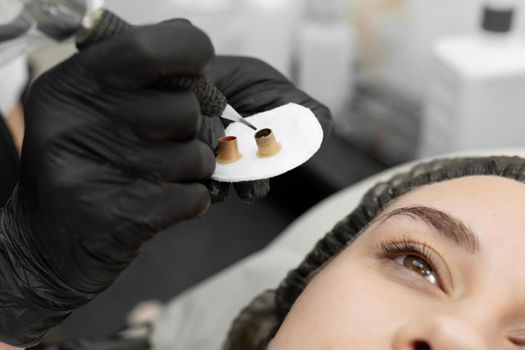 Permanent eyebrow makeup procedure, eyebrow tattooing. The master types paint in the tattoo machine.