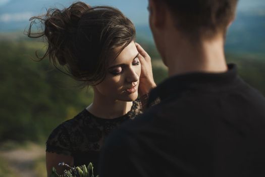 Woman and man in black clothes outdoors. Black wedding dress.