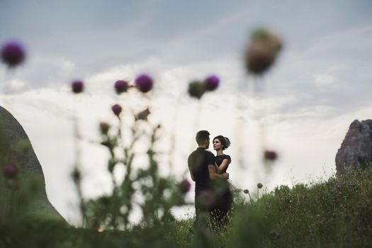 Woman and man in black clothes outdoors. Black wedding dress.