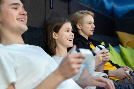 Group of friends of teenagers, boys and girls playing video games on a console in a game club.