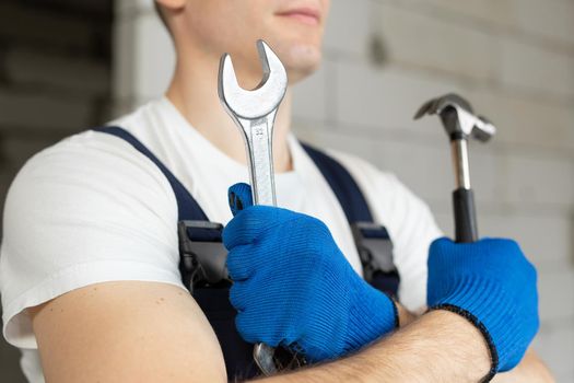 Male construction worker wearing a helmet with a hammer and a wrench