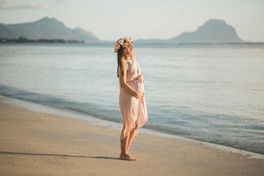 Pregnant woman in a beautiful dress on the ocean.