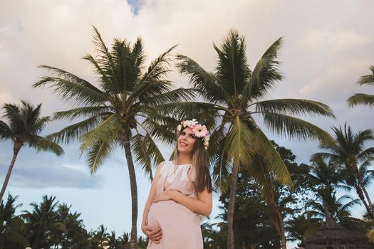 Pregnant woman in a beautiful dress on the ocean.