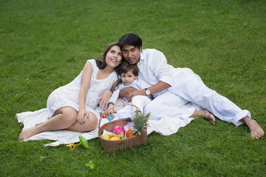 Family picnic of a happy family in the park on a green lawn.