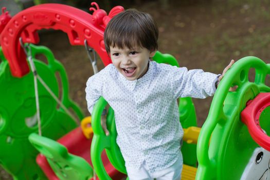 A little boy is playing on the playground.