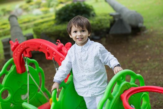 A little boy is playing on the playground.