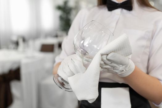 Close-up of a glass and a towel in the hands of a waiter. Preparation, table setting.