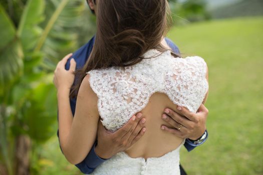 The groom hugs the bride at the wedding.