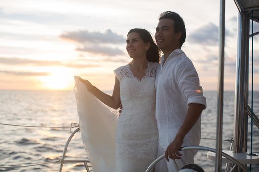 The bride and groom on a catamaran. The sunset in the open Indian ocean.