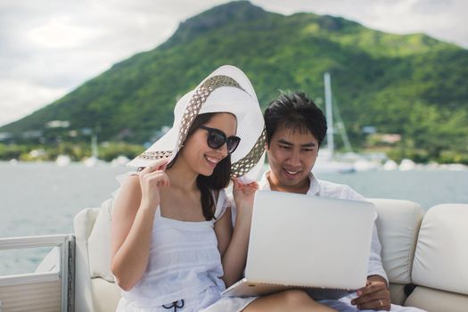 Two business people working with laptop on a sailing boat - sailing trip.