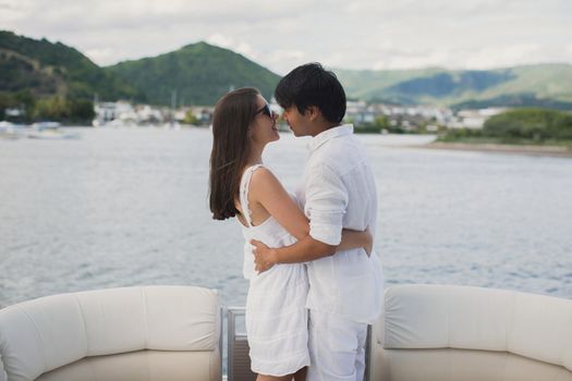 Young couple is traveling on a yacht in the Indian ocean. Man and a woman stand on the edge of the boat and kiss