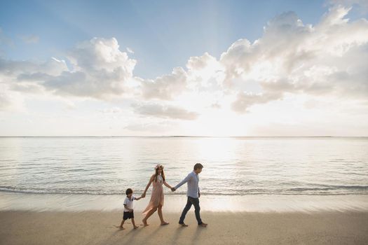 Pregnant mother, father and son walking on the beach