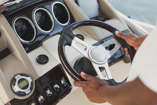 Yacht's captain holds the wheel with his hands