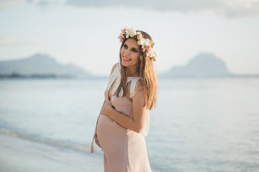 Pregnant woman in a beautiful dress on the ocean.