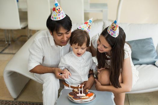 Happy family blowing candles together for a birthday at home