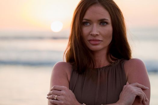 Beautiful woman on sunset background. Colorful dawn over the sea. Carefree woman enjoying the sunset on the beach. Happy lifestyle