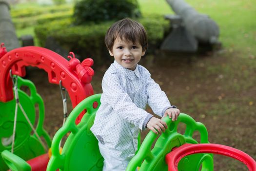 A little boy is playing on the playground.