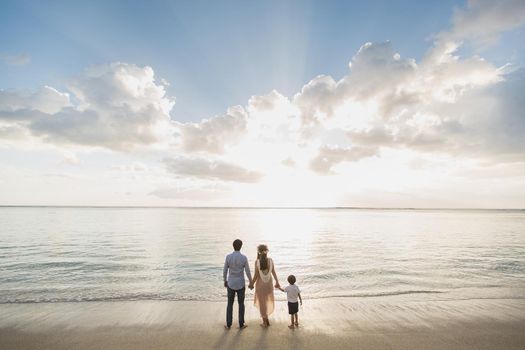 Pregnant mother father and son on the beach, delighted the sunset.