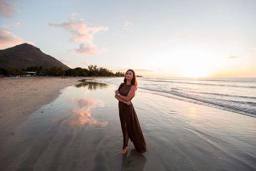 Beautiful woman on sunset background. Colorful dawn over the sea. Carefree woman enjoying the sunset on the beach. Happy lifestyle