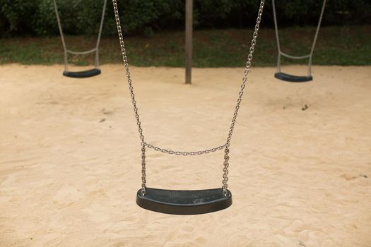 Swing set seat hanging on metal chains at a playground