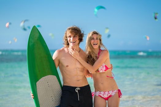 Young couple on beach with surfboard in arm. Surfing and outdoor sport lifestyle concept.