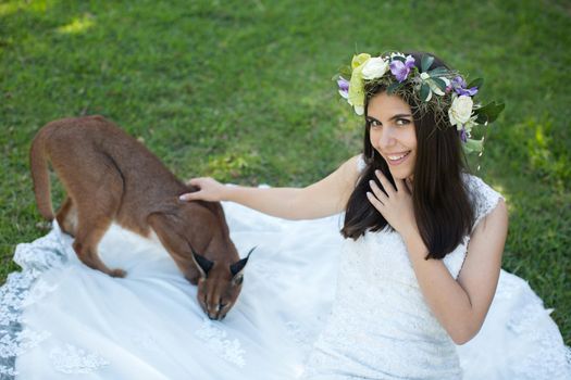 A bride in a white dress with a live trot on a green lawn.