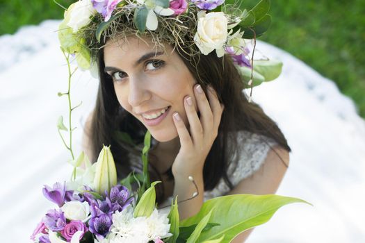 Beautiful young bride in a wreath with a bouquet in hand
