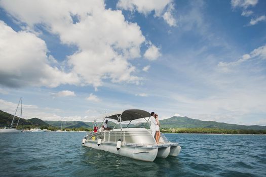 Young couple is traveling on a yacht in the Indian ocean. On the bow of the boat, a loving family embraces