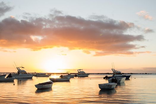 Small boats in the ocean at sunset.