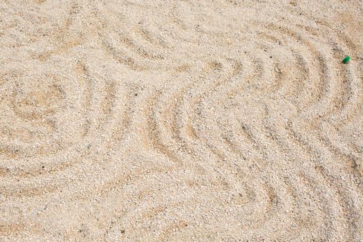 A pattern on the yellow sand of a round shape on the shore.