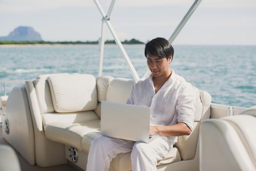 Businessman working with computer on a boat, nice outdoor office