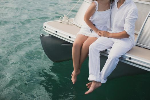 Young couple is sailing on a yacht in the Indian ocean. Man and woman sit on the edge of the yacht