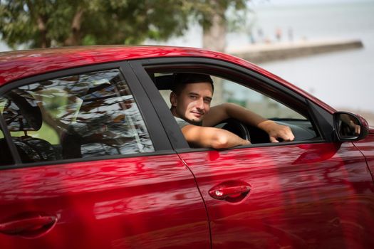 Driver sits behind the wheel in the red car.