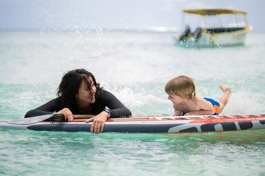 Mom and son have surfing in the ocean on the blackboard