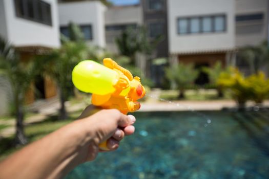 Man fires a water gun into a woman, while having fun in the pool.